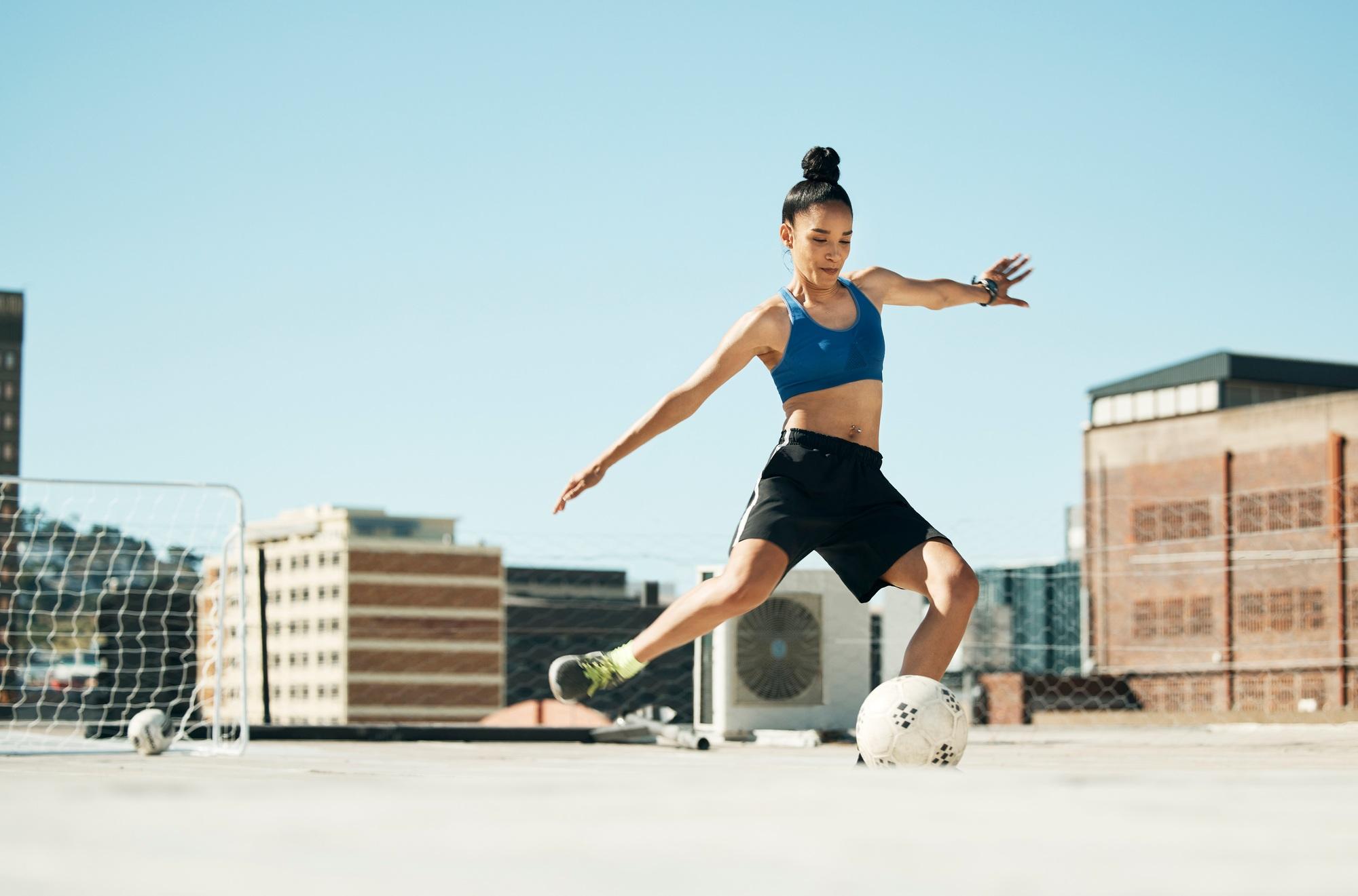 Soccer player, woman and soccer ball kick in fitness, training or exercise on Portugal city buildin